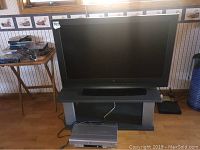 Westinghouse TV on gray TV stand with Sylvania DVD player on floor, front view