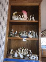 Shelves filled with ceramic geese and duck figurines of various sizes and colors.