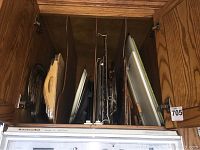 View of the wooden cabinet organizer with trays, cooling racks, and cutting boards stored vertically.