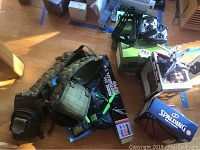 Image shows a hunting vest, remote control airplane, and other miscellaneous items on the floor under sunlight.