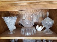 Wide view of the set including tall cut glass vase, glass swan figurine on base, covered candy dish, and small decorative swans.