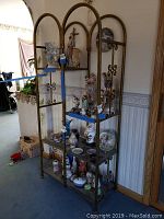 Front angle view of tall metal and wood decorative shelving unit with items on shelves