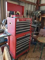 Full view of stacked red Craftsman top chest and bottom cabinet toolbox in workshop, items on top