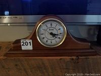 Front view of Dumai wood case mantle clock showing the entire wooden arch-shaped case and clock face.