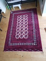 Full view of red and ivory hand-knotted wool rug on wood floor