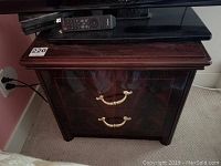 Front full view of the nightstand showing the high gloss dark wood finish, the top surface, two drawers, and brass curved handles.