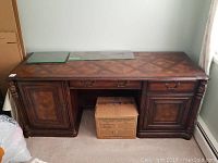 Front and top view of carved wood executive desk showing inlay design and brass handles