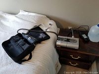 CPAP machine on nightstand alongside carrying case, hose and water reservoir