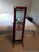 Front view of wooden jewellery stand with full-length mirror on the door.