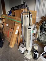 Photo showing Jiffy steamer, ironing board, tower fan, two desk fans, shelf, and small iron grouped together