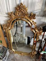 Full view of the ornate gold framed mirror with detailed carvings on frame and arched top