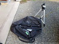 Tripod with black carrying bag open showing folded light stands and cords inside