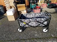 Side view of collapsible foldable wagon showing metal frame, camouflage fabric, and wheels.