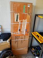 Boxed workbench leaning against pegboard showing original packaging strapped with white bands