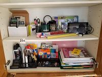 Shelf with various general office supplies including scissors, rulers, pens, folders, and air dusters