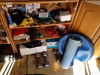 Wide view of the fitness items arranged in cabinet shelves and floor including resistance bands, balance trainer, dumbbells and yoga mat.