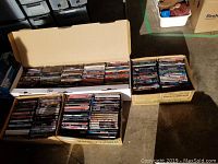 Four cardboard and shipping boxes lined with rows of DVD cases