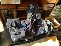Three items laid on a table: one wetsuit and two vests, all black with blue and gray accents.