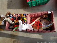 Image showing two large plastic bins: one contains assorted dolls and the other contains a wooden train set with various track pieces and a small green tractor toy.