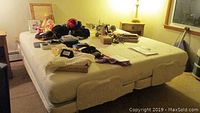 Full view of king size adjustable bed with mattress and various items on top