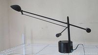 Photo of adjustable black desk lamp with counterbalance weights on a white table.