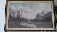Framed lithograph titled Sierra Sunrise showing a river, forest, and mountain landscape with cloudy sky.