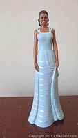Figurine of Michelle Obama wearing a sky blue dress with silver horizontal stripes, standing 8 inches tall, from Hamilton Collection.