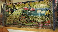 Large vintage peacock tapestry displayed hanging on wall showing detailed colorful peacock, floral design, swans on pond.