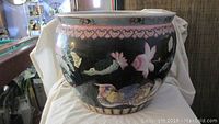 Large Asian style ceramic pot with bird and lotus designs on black background