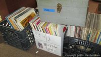 Three black plastic crates filled with LPs and grey portable record case on top