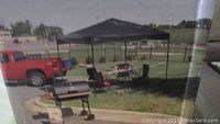 Outdoor setup of black roof pop up canopy tent with metal frame in a yard, showing size and use scenario