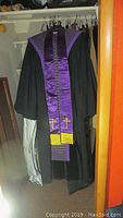 Photo of black robe with purple satin stole hanging in closet
