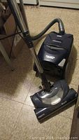 Full vacuum with hose and power nozzle attachment on the floor.