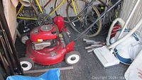 Photo of red Craftsman push lawnmower alongside bicycles and various tools, showing overall size and condition of the mower
