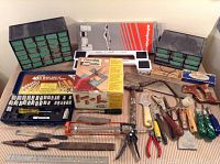 Front view of mixed hand tools, including vintage Copolymer Joint Master set in box, assorted screwdrivers, pliers, hand saw, metal ruler, and two multi-drawer storage caddies.