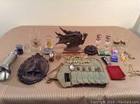 Overview of mixed lot including metal collectibles, glassware, dragon figurine, spoons, and cards.