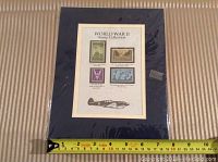 Full mounted stamp collection on display sheet placed on striped fabric with measuring tape showing about 9 inches tall.