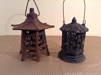 Front view of two cast iron pagoda garden lanterns with visible rust and paint loss.