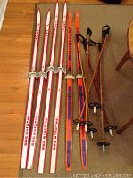 Full view of three pairs of cross country skis and three pairs of bamboo ski poles arranged on a floor.