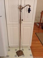 Full view of antique bridge lamp standing upright, showing height, base, and arm design