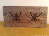 Full view of the barn board coat rack showing two rustic double hooks attached to weathered wood