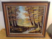 Framed oil on canvas painting of a forest landscape showing autumn trees and a stream, measuring 28x24 inches.