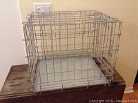 Front view of the entire folding metal dog cage showing wire construction and metal floor tray inside.
