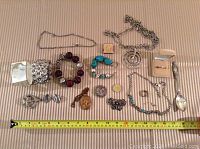 Full view of all jewelry pieces arranged on a striped cloth with measuring tape for scale.