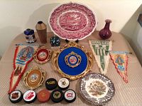 Full view of lot showing large Mason Vista platter, decorative pennants, hockey pucks, metal and porcelain vases, metal frame with blue backing and cameo-style picture.