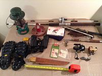 Wide view of lot showing fishing rods, lantern, anchor, crampons, binoculars, knife and fishing accessories.