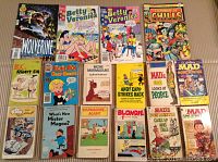 Photo of 16 vintage comic digest books arranged in rows on a beige surface showing front covers with various colorful designs and titles.