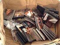 Box filled with loose CD jewel cases in varied condition and some discs inside cases
