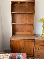 Two-piece wooden cabinet set by Thomasville with a lower cabinet featuring doors and a removable upper bookcase with shelves.