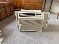 Front view of the Sharp window air conditioner on carpeted floor.